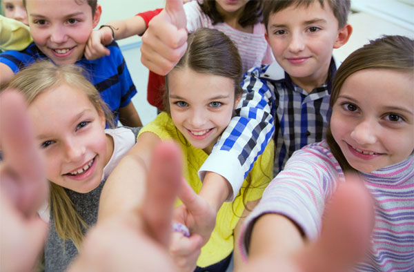 Fröhliche Schulkinder, die den Daumen hoch zeigen