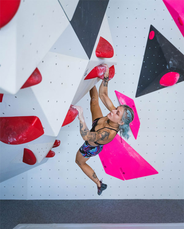 urbanapes_boulderhalle_hamburgwest_600x740 Frau hält sich an roten Griffen fest an der Boulderwand in urban apes Hamburg West