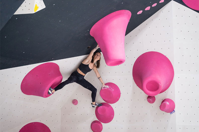 urban apes Hamburg St. Pauli Frau beim Bouldern zwischen großen pinken Griffen