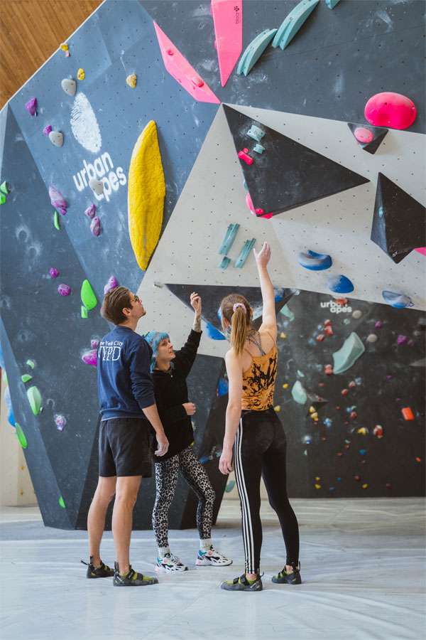 Drei Leute stehen neben der Boulderwand und besprechen gemeinsam eine Route.