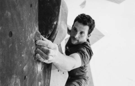 Boulderer hält sich an kleinen Griff fest, Bild in Schwarzweiß