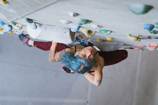 Kletterin beim Vorstiegsklettern schaut an der Kletterwand nach oben.