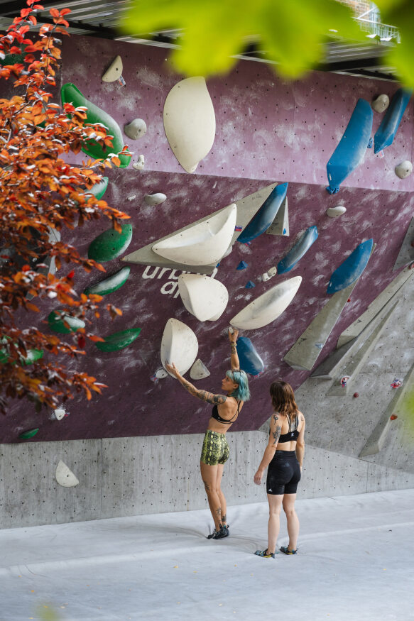 Zwei Boulderinnen stehen vor einer Boulderwand im Aussenbereich vom urban apes Bright Site.