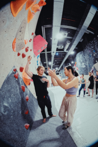 Trainer erklärt Teilnehmerin Bouldern